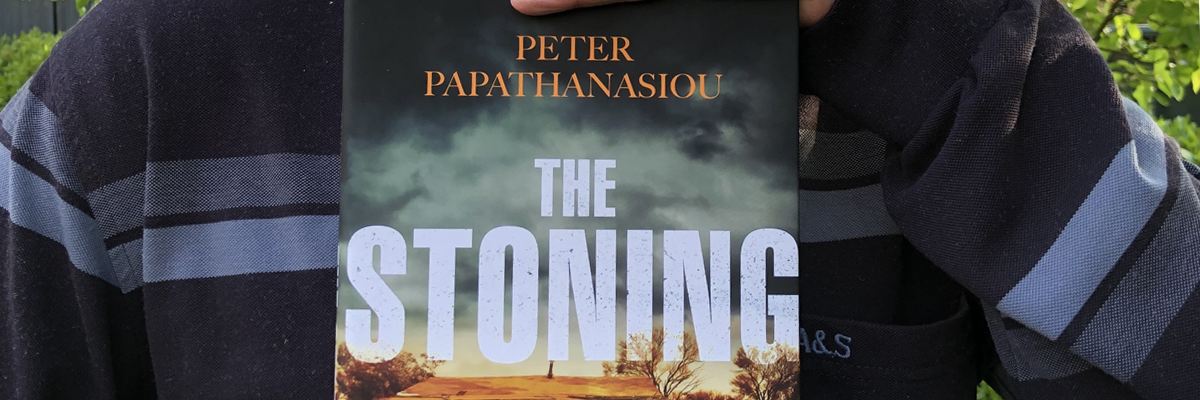 The cover of Peter's novel The Stoning, held by Peter.