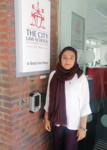 Khadija stands next to the City Law School sign. 
