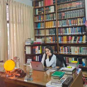 Khadija sits by a desk in a large office. 