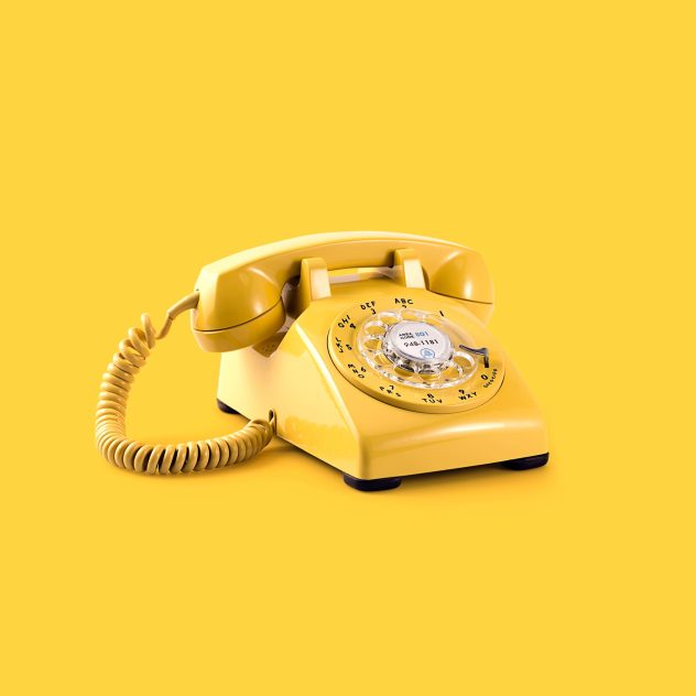 Photograph of yellow telephone set on yellow background