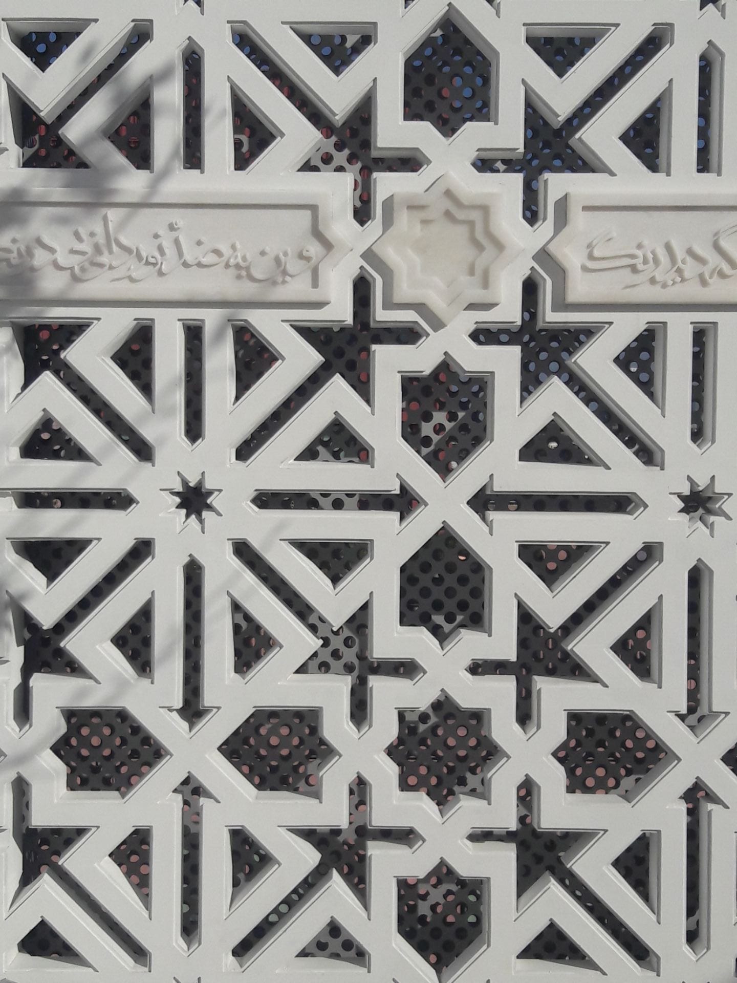 Detail from the white trellis in the Garden of Light with 8 pointed star design and extract from the Qu'ran.