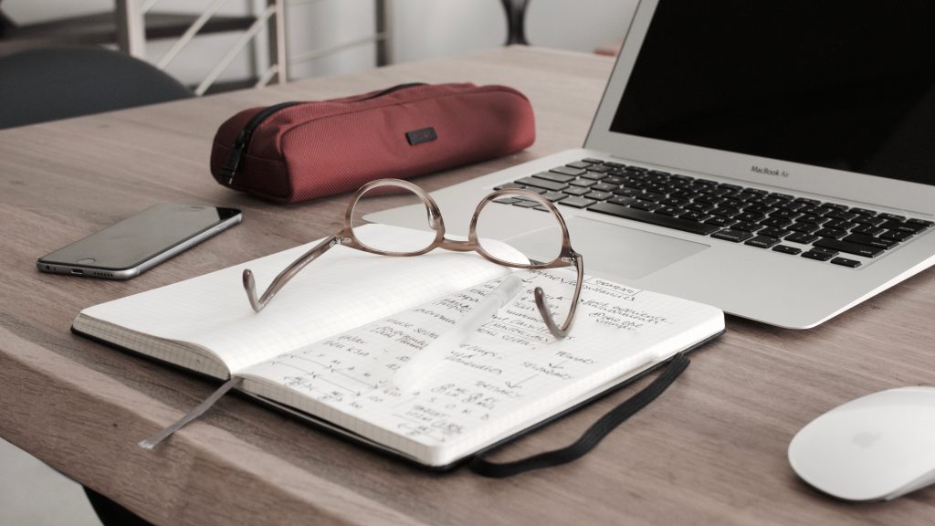 notebook and glasses in front of comptuer