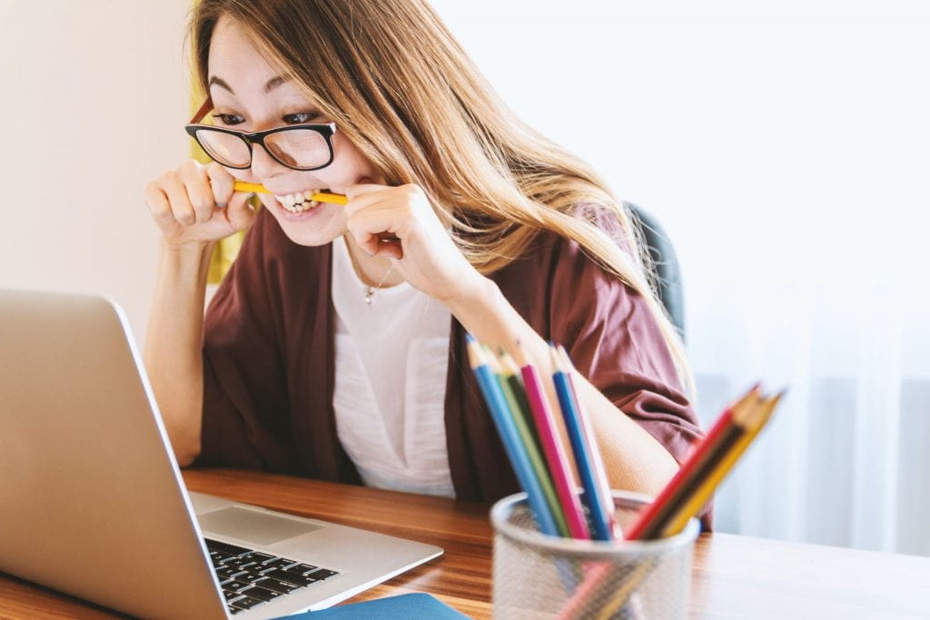 Woman biting pencil while sitting in front of computer