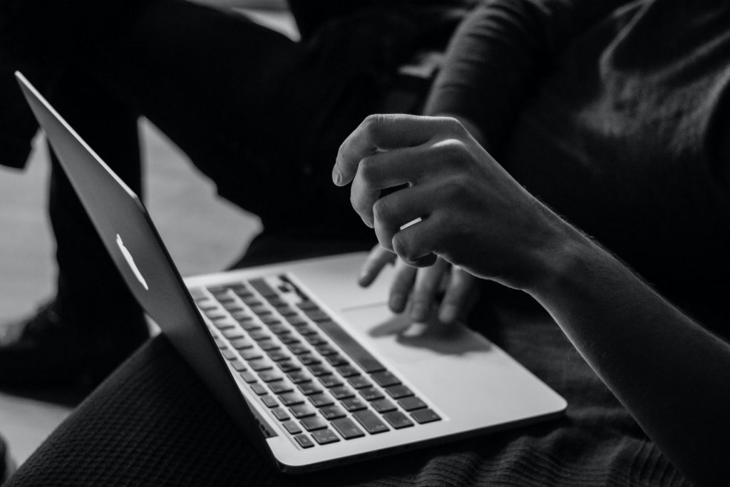 person's hands on computer moving the trackpad in black and white