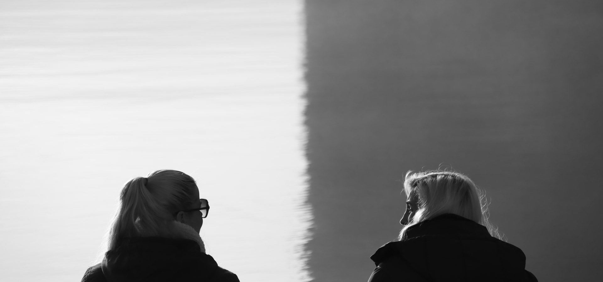 black and white photo of two people looking at each other, backs towards the viewer