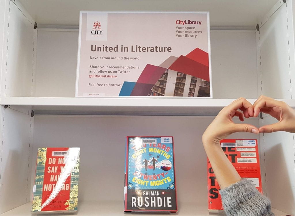 An image of a past book display of fiction books at Northampton Square Library, entitled "United in Literature", along with hands forming a heart symbol