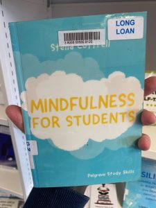 A hand is holding a print copy of 'Mindfulness for Students,' by Stella Cottrell