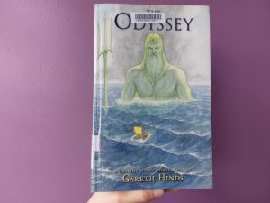 A hand is holding Odyssery: a graphic novel adaptation by Gareth Hinds